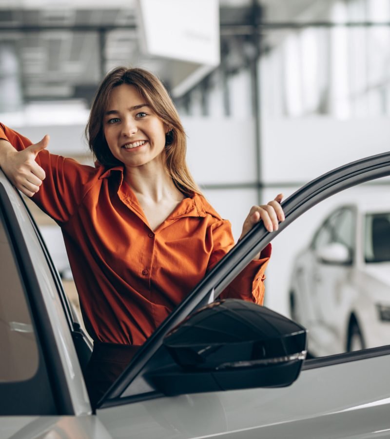 Woman choosing a car in a car showroom